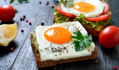 Rye toasts with mashed avocado, fried egg, fresh tomato, herbs. Tasty breakfast. Proper nutrition. Sandwich with egg.