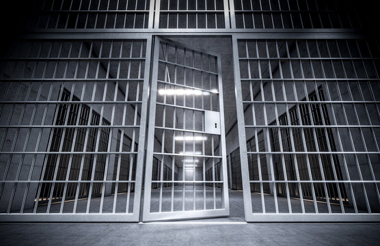 corridor of a prison with bars and open cell door.