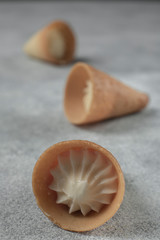 Three waffle cones with cream large on a gray textural background.