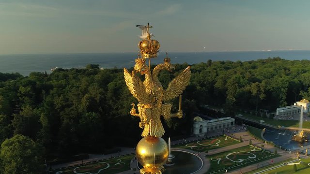 Close up golden three-headed eagle top symbol royal Russia Saint Petersburg suburban old imperial palace. Historical famous museum. Seagull flies and sits on top. Cascade fountains. Aerial around