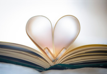 Corazón con hojas de libro y añillos de matrimonio