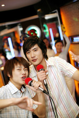 Two men singing together in karaoke bar
