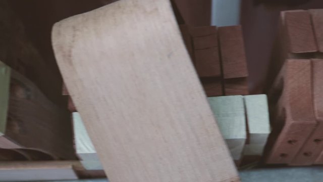 Rack of unfinished handmade wooden guitar heads. Handheld panning shot