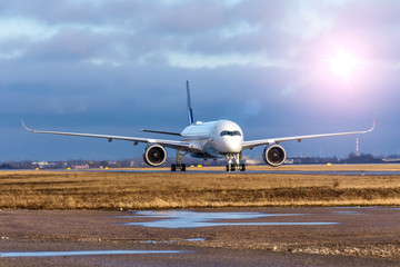 Fototapeta na wymiar Plane lit by the evening sun travels through the runway after landing.