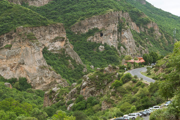 Spectacular drone view of winding road with parked cars in highland area with rough rocks covered with forests 