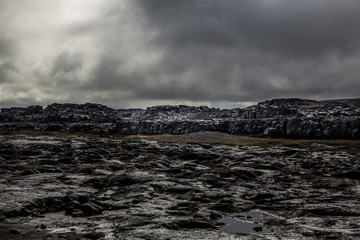 General view of the desert near the Detifoss waterfall in the north of Iceland. The sky is cloudy. The desert is made up of dark volcanic stones covered with greenish moss