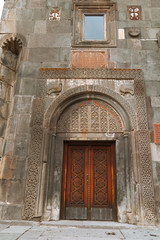 Low angle of arched entrance in old stone church with ornamental wooden door