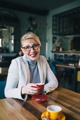 woman posing , holding cup of coffee in cafe