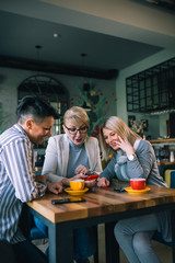 women friends having coffee break at cafe, using mobile phone