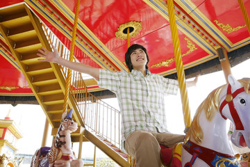 Man spreading his hands while riding on carousel