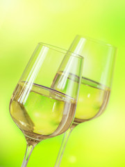 Two glasses of white wine served with cheese board on light green background. Wine mood concept