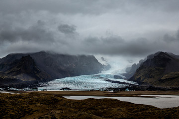 Mountain landscape in Iceland. in the distance you can see the Sólheimajökull glacier with a sky very cloudy above. The sky is not visible and no ray of sunshine passes through