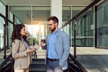 Obraz premium Couple of cheerful colleagues talking on business break