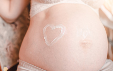 A closeup of a pregnant woman's tummy, with a heart drawn around her belly button.
