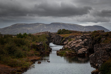 landscape on Pingvellir site in central Iceland. There is a river flowing between two oceanic plates, one is America and the other is Europe