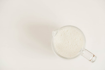 Obraz na płótnie Canvas Glass jug with milk on a white table. Top view. Copy, empty space for text