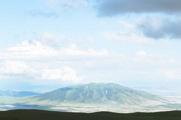 Picturesque mountain litting by sunlight. Amazing summer landscape of highland valley and blue sky with clouds