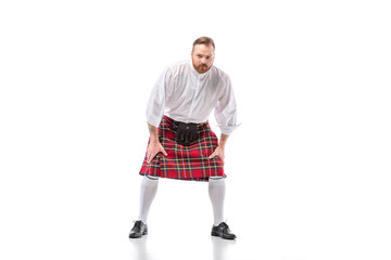 Scottish redhead man in red kilt in pose on white background