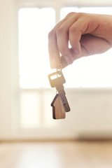 Home key in hand in apartment on empty room background