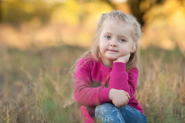 Little beautiful girl blonde sits in a field close-up. Children's Day concept