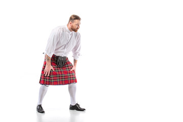 Scottish redhead man in red kilt in pose on white background