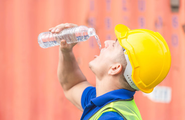 Close up of Worker man in hard hat drinking water at containers cargo