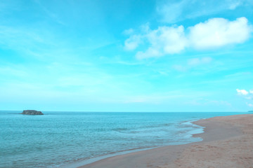 Beautiful calm ocean waves reaching tropical sandy beach on sunny blue sky background with puffy fluffy clouds & white cloudscape in morning sunlight & sun rays at daylight sunshine day, free space  