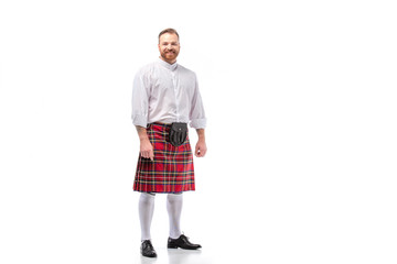 smiling Scottish redhead bearded man in red tartan kilt on white background