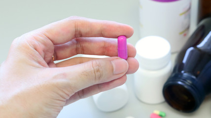 Woman hands holding a purple capsule of Clindamycin, used to treat bacterial infections, or treat patients who have an allergic reaction to penicillin. Isolated with colorful drugs, pills and tablet.
