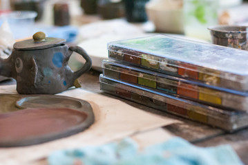Obraz na płótnie Canvas Watercolor in the plastic box set pile up on the table beside ceramic work elephant mug