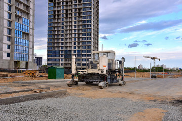 Slipform paver machine on road work at construction site. Highway concrete paving in the new quarter. Repairing concrete roads using new technology