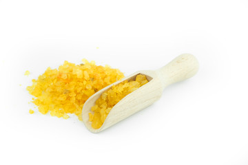 Yellow sea spa salt with wood scoop isolated on white background.