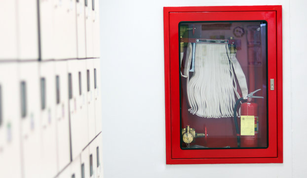 Red Fire extinguisher and fire hose reel setting in laboratory walkway industrial control system with fire alarm controller, for evacuation escape plan response for emergency situation in industry.