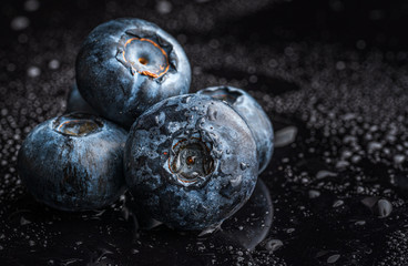 One blueberries covered with water drops isolated on black background. Copy space for text. Selective focus