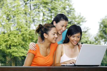 Three women using laptop at the park