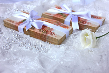Fototapeta na wymiar Packs of Russian banknotes and a bow with a gift ribbon, on a background of lace. Dowry and ransom of the bride, birthday present, cash prize.