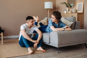 couple in home made clothes. lean on a sofa, sit on a warm wooden floor, spend time together with your beloved.