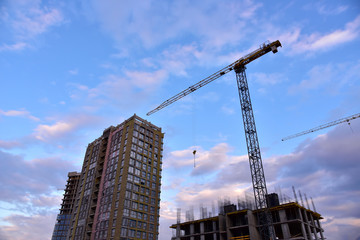 Fototapeta premium Tower crane in action on sunset sky background