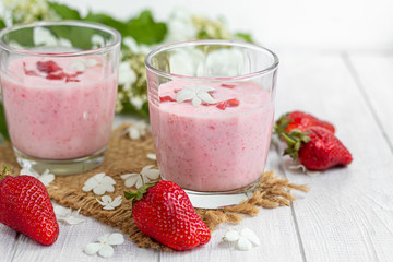 Strawberry and yogurt smoothies on a white background. Decorated with elderberry flowers and strawberries. Healthy nutrition, diet.