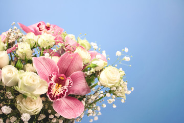 Close up of beautiful bouquet of orchids, roses and gypsophila, Baby's-breath flowers in decorative paper tube packaging on pink background with copy space. Selective focus, celebrating concept