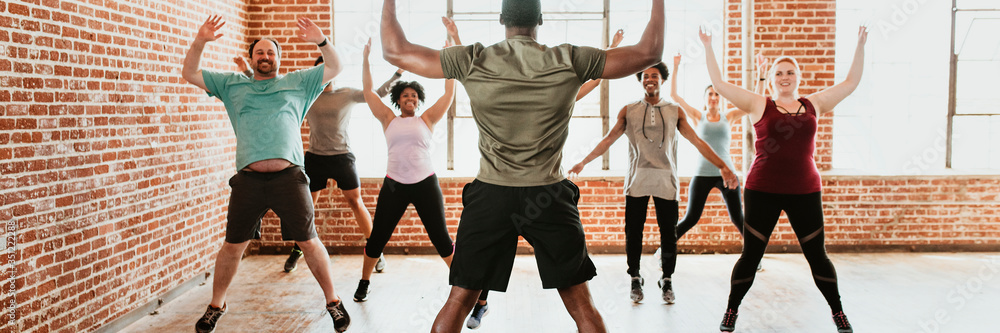 Wall mural trainer and his students stretching in a studio