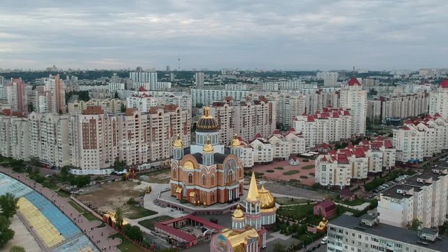 Aerial photography. Orthodox Christian Church on the Obolonskaya embankment in the spring in Kiev. Many houses built along the Dnieper Bay. Drone.