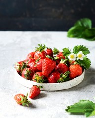 Fresh strawberries in a bowl on a gray background, still life