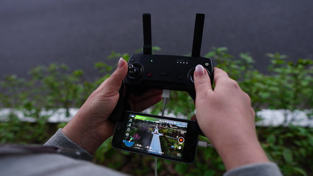 Woman operating a drone using a remote controller. Close up picture. The picture on the phone. A look in the center