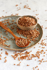 Raw dry buckwheat grain  on a plate with a spoon