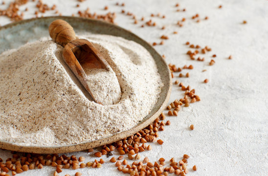 Buckwheat flour on a plate with a spoon and buckwheat grain