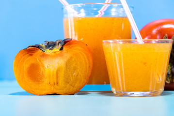 Fresh fruit juice and persimmon (Diospyros kaki L.) on blue background