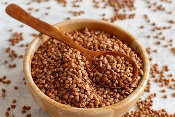Raw dry buckwheat grain  in a bowl with a spoon