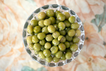 Top view of pickled cooked green peas in jar on blur background.