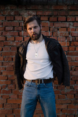 Obraz premium Bearded man posing against a brick wall.
